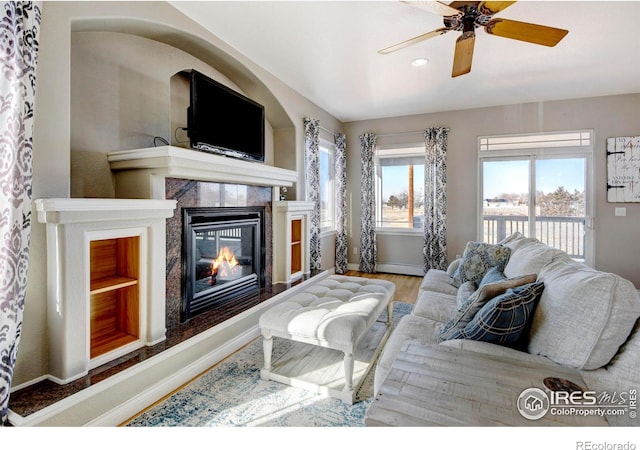 living room with baseboards, a ceiling fan, a premium fireplace, wood finished floors, and recessed lighting