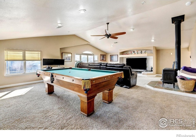 playroom with carpet floors, a wood stove, a healthy amount of sunlight, and vaulted ceiling