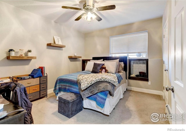 bedroom featuring a baseboard heating unit, light carpet, and baseboards