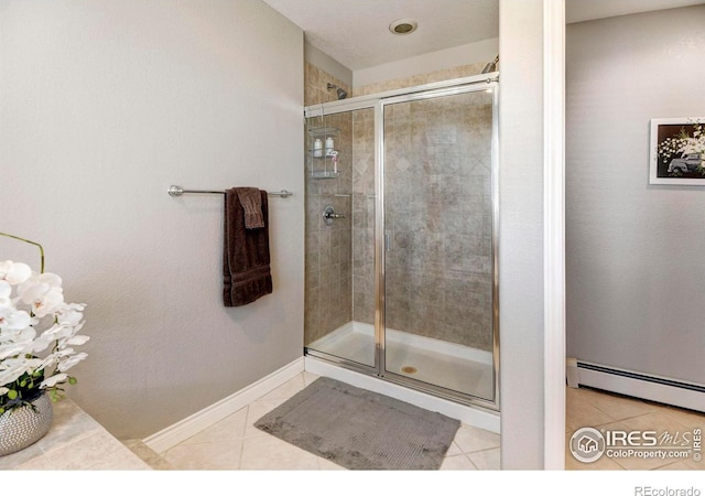 bathroom featuring a baseboard radiator, a shower stall, baseboards, and tile patterned floors