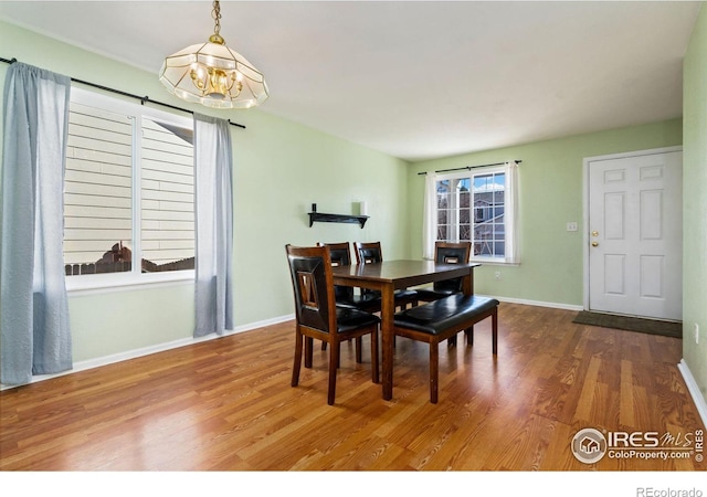 dining space featuring an inviting chandelier, baseboards, and wood finished floors