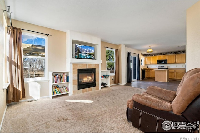 living room with a healthy amount of sunlight, visible vents, and dark colored carpet