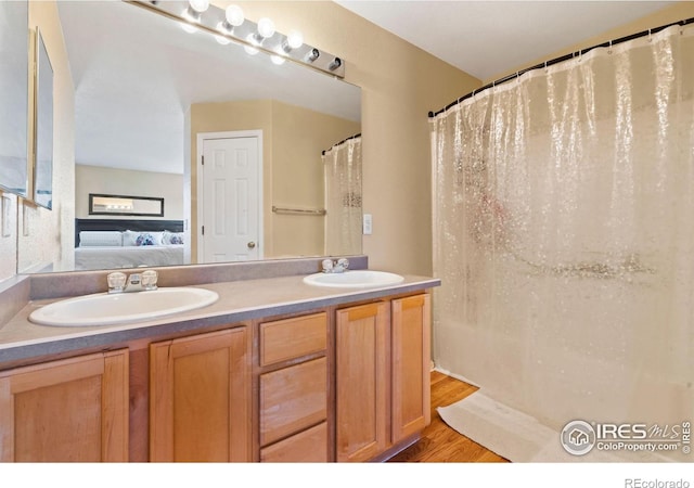 bathroom featuring double vanity, wood finished floors, a sink, and ensuite bathroom