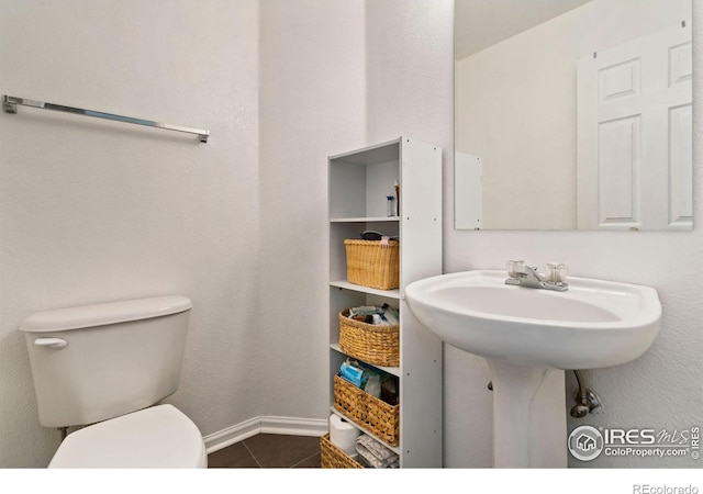 bathroom with baseboards, toilet, and tile patterned floors