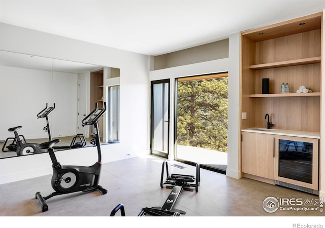 exercise room featuring built in features, wet bar, beverage cooler, and a sink