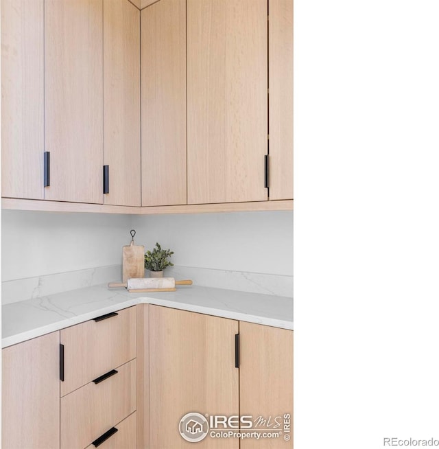 kitchen with light stone countertops and light brown cabinetry