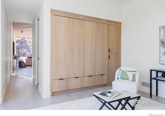 living area featuring light wood-type flooring, visible vents, and baseboards