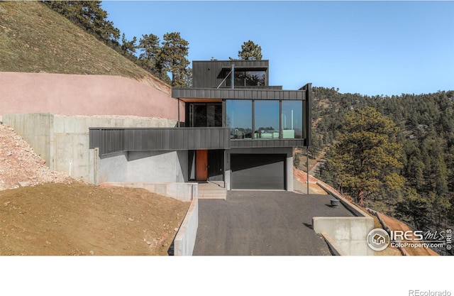 modern home with driveway, a balcony, and an attached garage