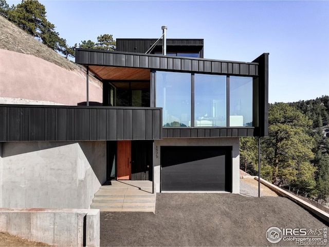 contemporary house with an attached garage, driveway, and stucco siding