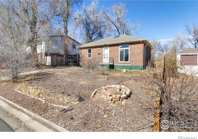 view of front of home with brick siding, fence, and roof with shingles