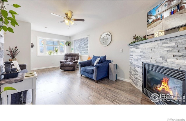 living room featuring a ceiling fan, wood finished floors, a fireplace, and baseboards