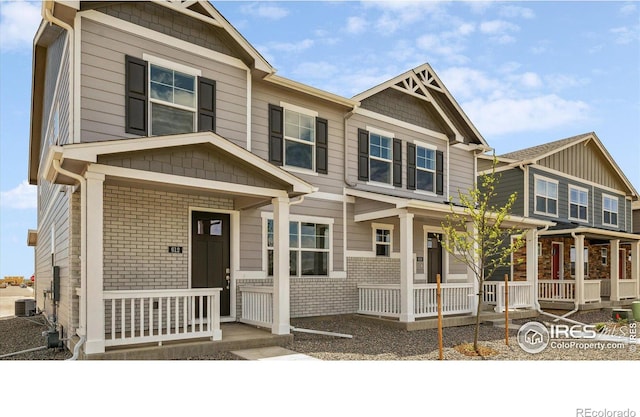 view of front facade featuring covered porch, brick siding, and central AC unit