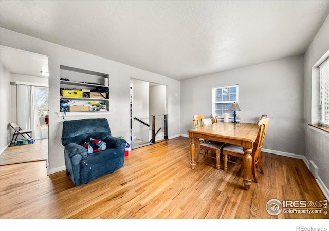 dining space with a wealth of natural light, visible vents, baseboards, and wood finished floors