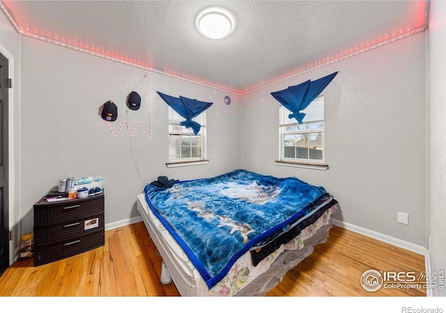 bedroom with multiple windows, a textured ceiling, and wood finished floors