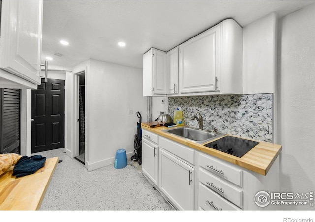 kitchen featuring decorative backsplash, white cabinetry, wood counters, and baseboards