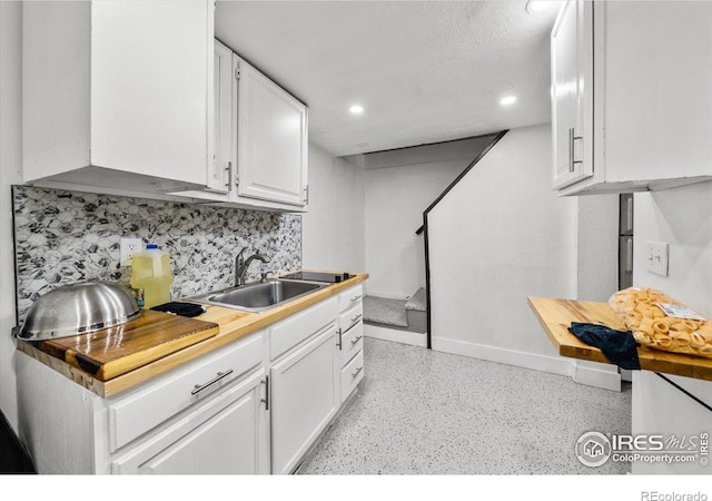 kitchen with light speckled floor, decorative backsplash, a sink, and white cabinets