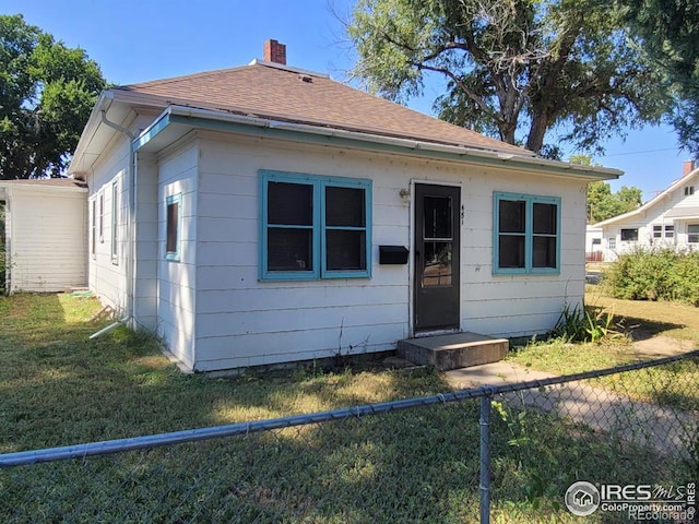 bungalow-style house featuring roof with shingles, a chimney, fence, and a front yard