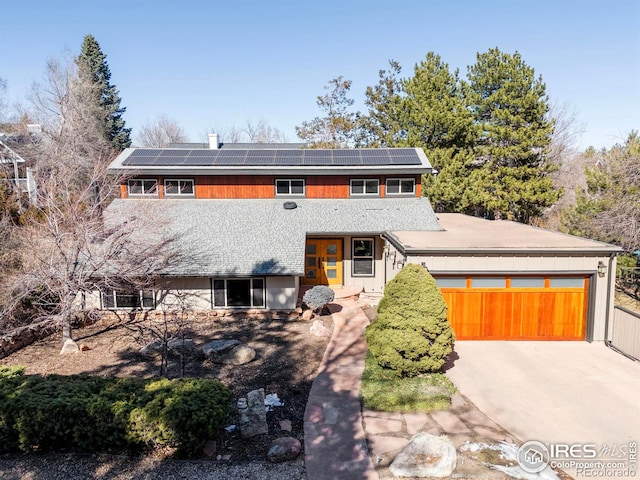 view of front of house featuring solar panels, concrete driveway, and an attached garage