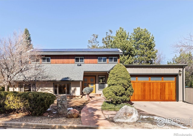 view of front of house with an attached garage, driveway, and roof mounted solar panels