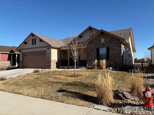 view of front of property with an attached garage, stone siding, driveway, and board and batten siding