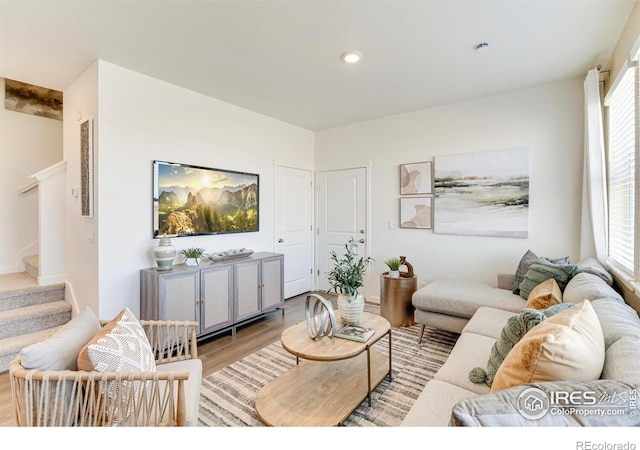 living room with light wood-type flooring, a wealth of natural light, recessed lighting, and stairs