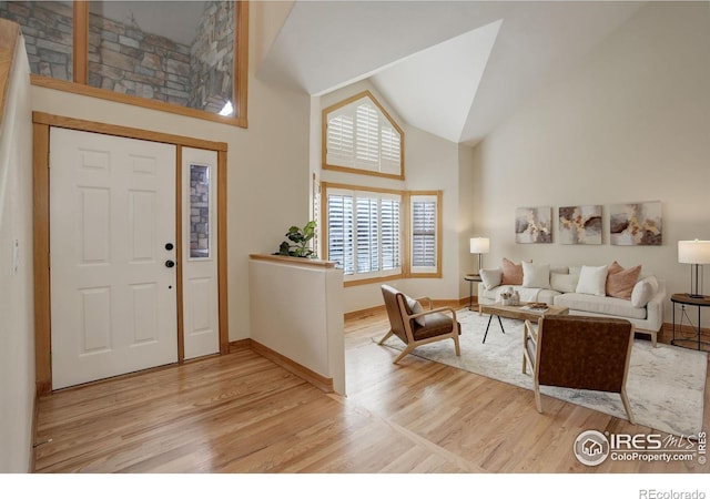 entrance foyer featuring light wood-style floors, baseboards, and high vaulted ceiling