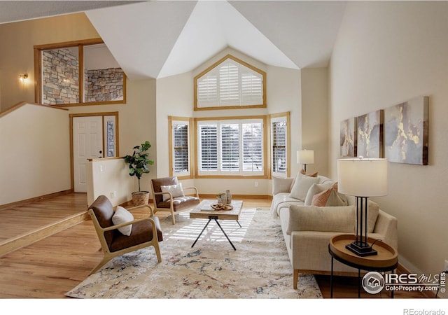 living room featuring baseboards, high vaulted ceiling, and wood finished floors