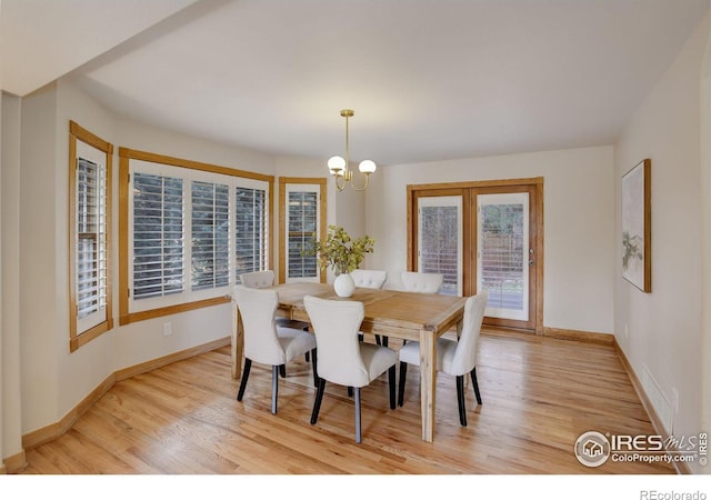 dining space featuring an inviting chandelier, light wood-style flooring, and baseboards