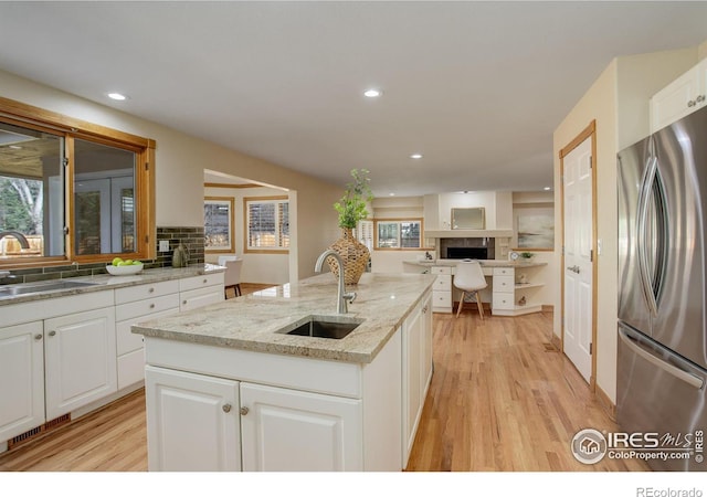 kitchen with light wood-type flooring, freestanding refrigerator, and a sink