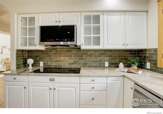 kitchen with appliances with stainless steel finishes, white cabinets, glass insert cabinets, and backsplash