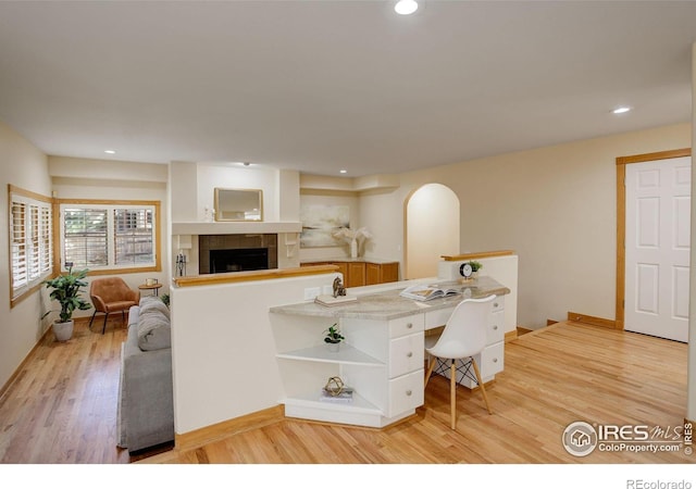 interior space with a tiled fireplace, light wood-type flooring, baseboards, and recessed lighting