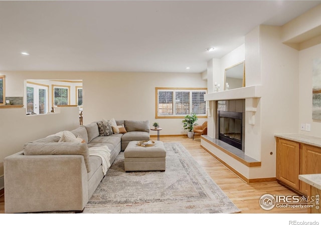 living area featuring light wood finished floors, recessed lighting, baseboards, and a tile fireplace