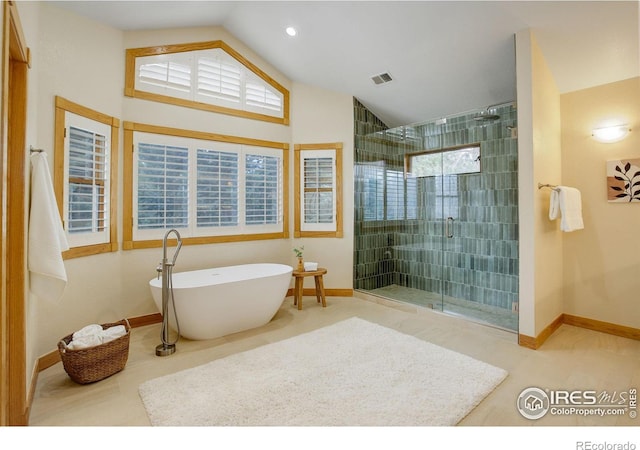 bathroom with lofted ceiling, a soaking tub, visible vents, a shower stall, and baseboards