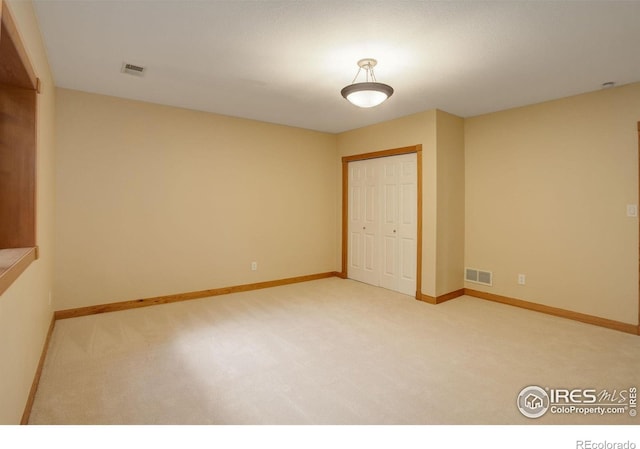 carpeted spare room with visible vents and baseboards