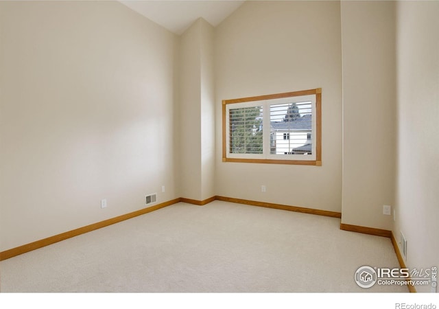 carpeted empty room with high vaulted ceiling, visible vents, and baseboards