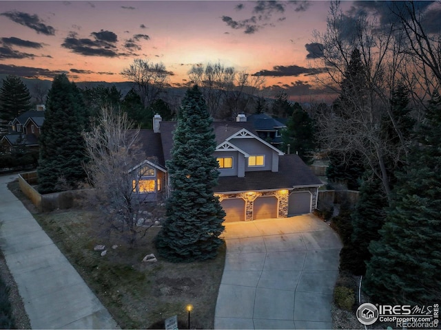 view of front of home with driveway, stone siding, and an attached garage