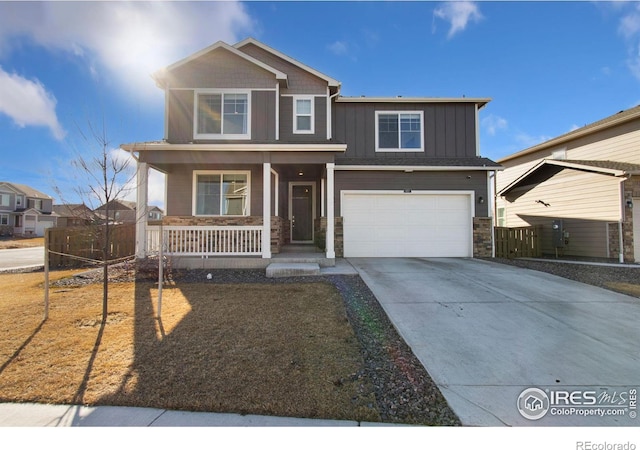 view of front facade with a porch, a garage, driveway, stone siding, and board and batten siding