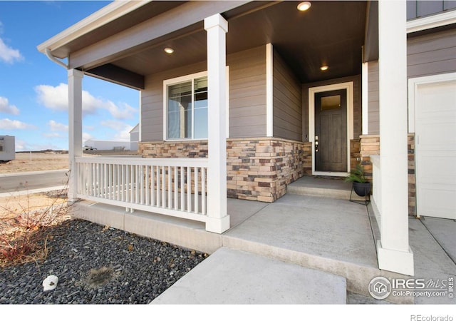 property entrance with a garage, stone siding, and a porch