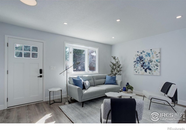 living room featuring recessed lighting, a textured ceiling, baseboards, and wood finished floors