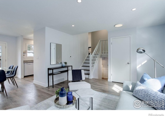 living room featuring recessed lighting, wood finished floors, visible vents, baseboards, and stairway