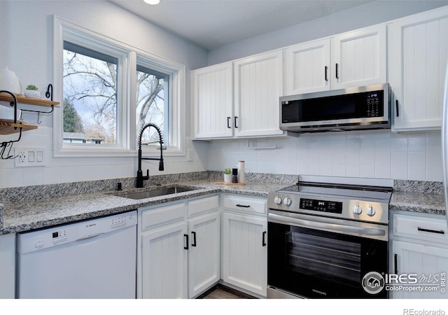 kitchen with stainless steel appliances, a sink, and white cabinetry