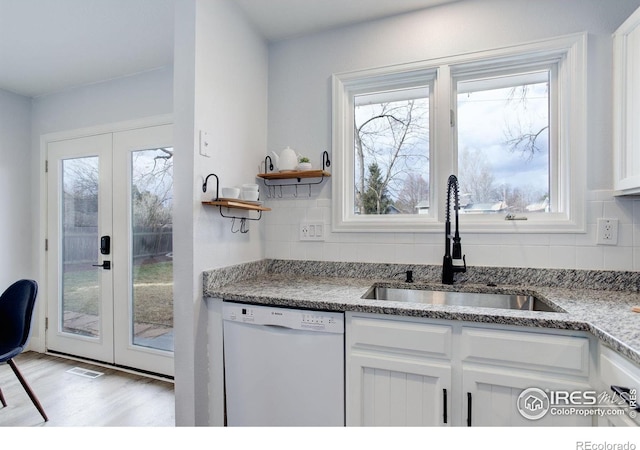 kitchen featuring decorative backsplash, white cabinetry, white dishwasher, and a sink