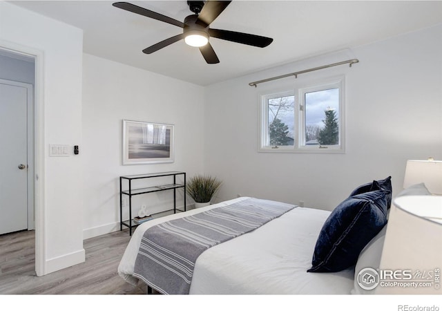 bedroom with a ceiling fan, baseboards, and wood finished floors