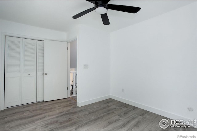 unfurnished bedroom with a ceiling fan, a closet, baseboards, and wood finished floors