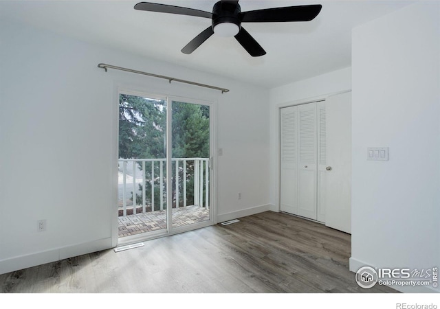 unfurnished bedroom featuring wood finished floors, a ceiling fan, baseboards, access to outside, and a closet