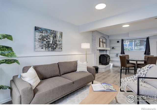 living room featuring a wainscoted wall, a fireplace, and wood finished floors