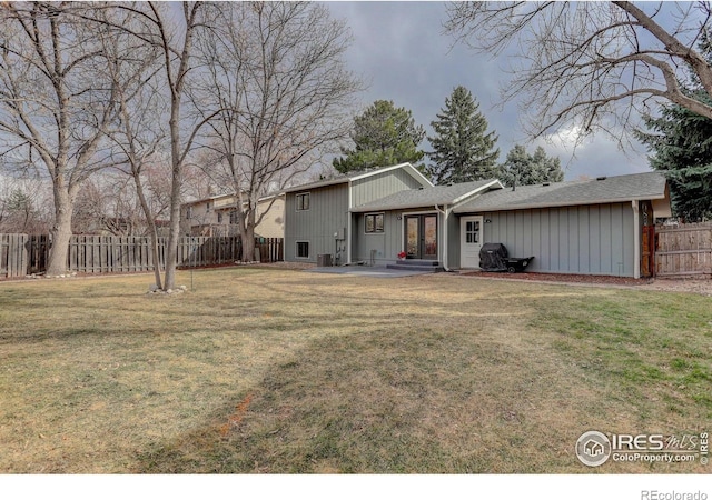 rear view of house featuring cooling unit, fence, french doors, and a yard