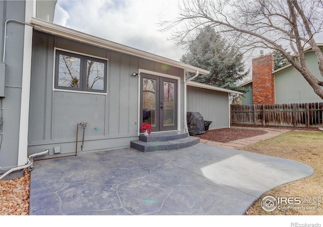 view of exterior entry featuring french doors, a patio area, and fence