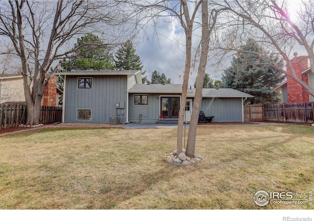 back of property featuring central air condition unit, a fenced backyard, a lawn, and french doors