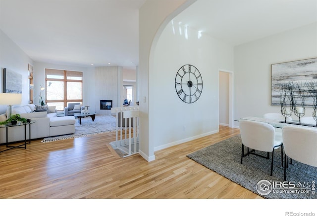 interior space featuring arched walkways, a fireplace, recessed lighting, wood finished floors, and baseboards